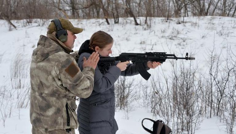 عسكري أوكراني يدرب فتاة مدنية على ضرب النار