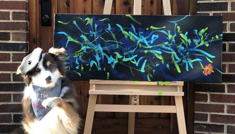 الكلبة إيفي بجوار إحدى لوحاتها الفنية