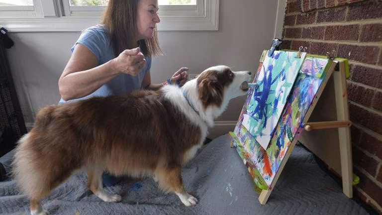 الكلبة إيفي بجوار إحدى لوحاتها الفنية