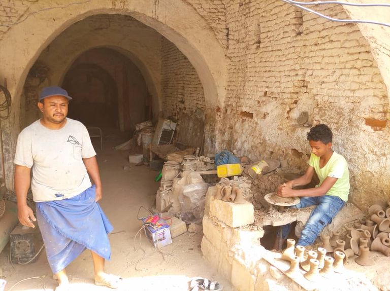 حرفي ينقل أواني فخارية داخل المصنع الوحيد المتبقي في حيس اليمنية