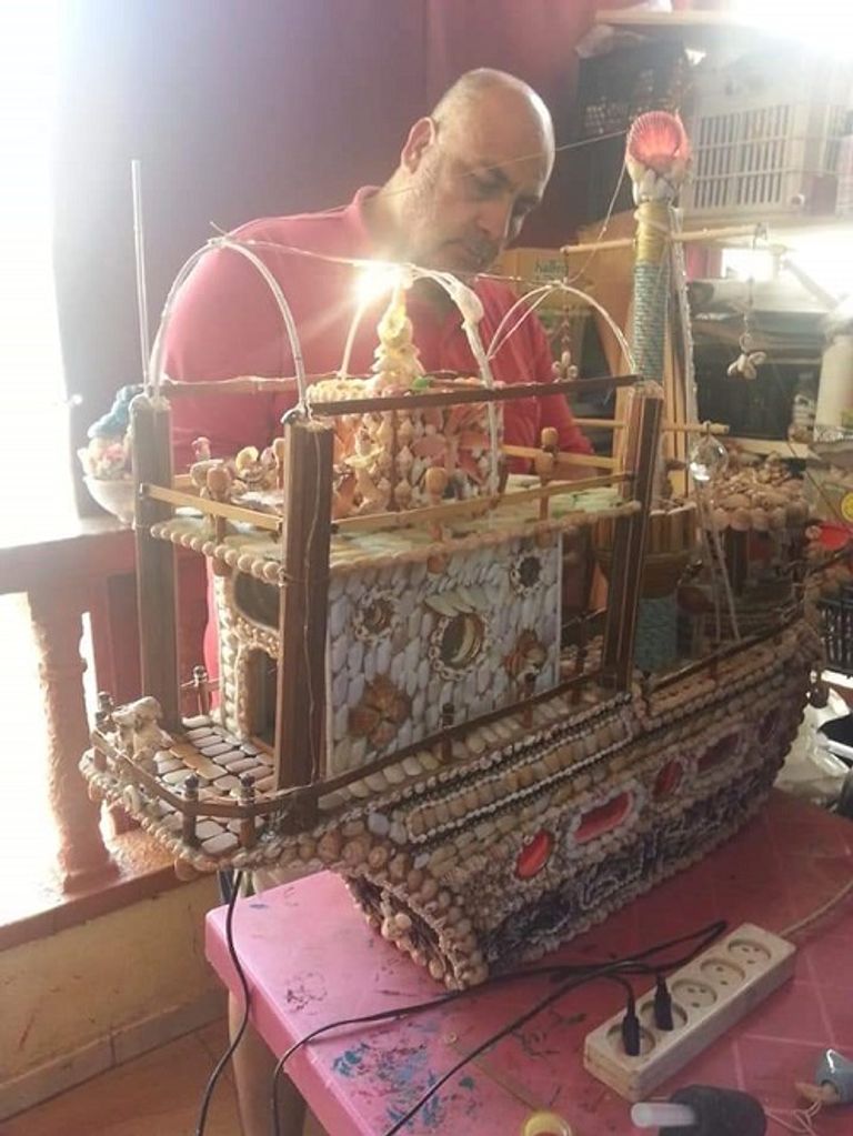 عدنان يحمل إحدى التحف التي صنعها من الصدف