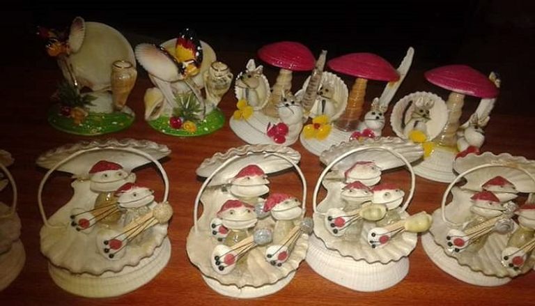 عدنان يحمل إحدى التحف التي صنعها من الصدف