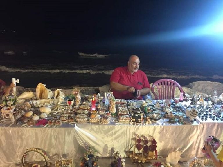 عدنان يحمل إحدى التحف التي صنعها من الصدف