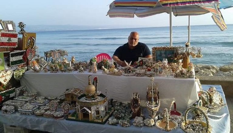 عدنان يحمل إحدى التحف التي صنعها من الصدف