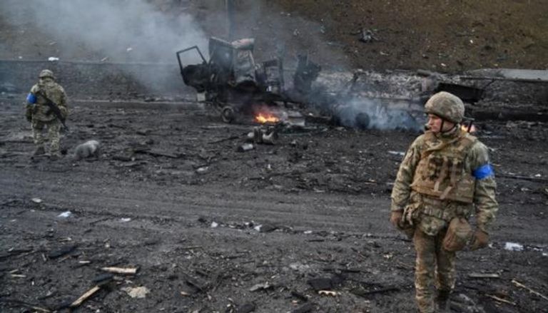 جنديان أوكرانيان إلى جانب آلية محترقة