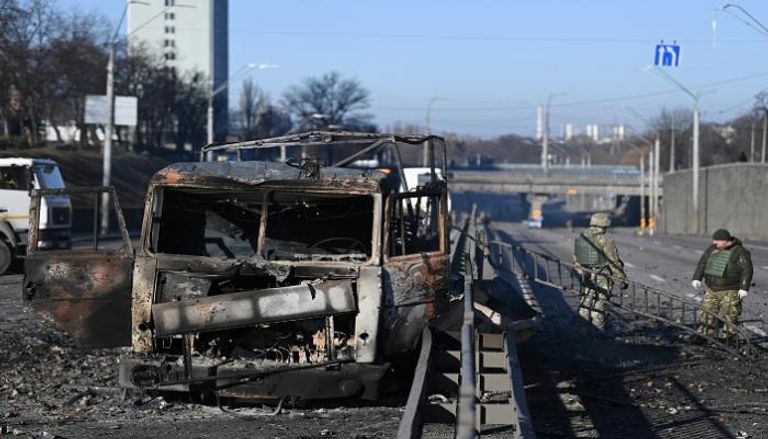 جنود بجوار إحدى المعدات العسكرية المحترقة في كييف