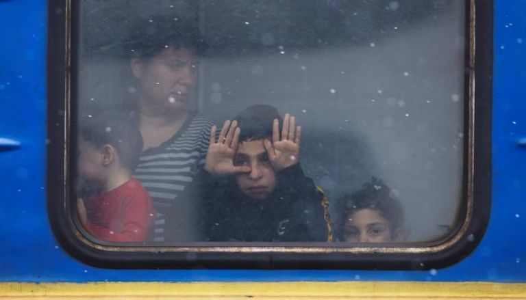 أطفال يطلون من نافذة قطار لنقل الفارين من مناطق المعارك بأوكرانيا