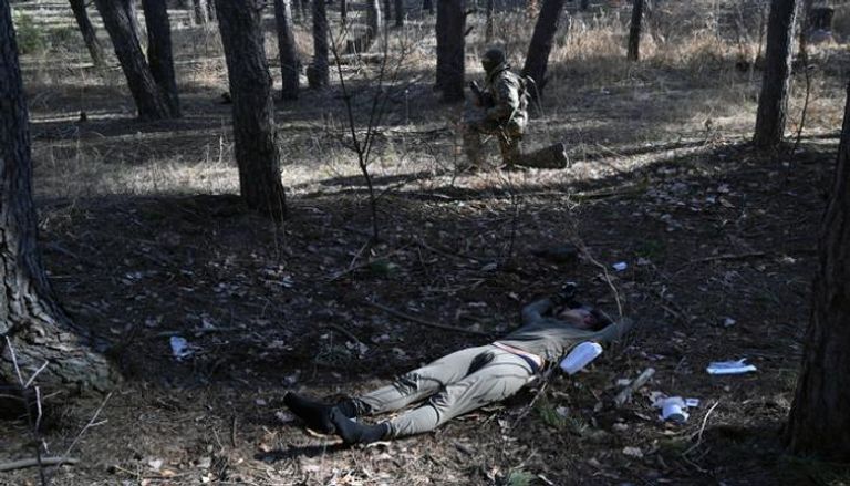 جندي أوكراني بجوار جثة مظلي روسي شمال كييف (أ. ف.ب)