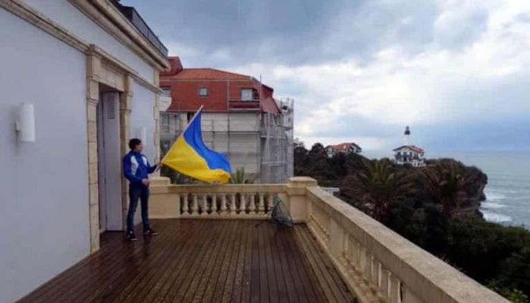 رجل يلوح بالعلم الأوكراني من شرفة منزل صهر بوتين
