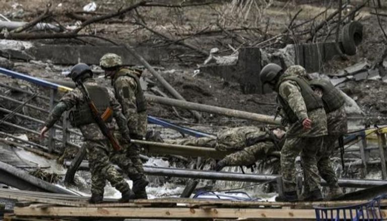 جنود أوكرانيون يحملون أحد الجرحى شمال كييف- أ.ف.ب