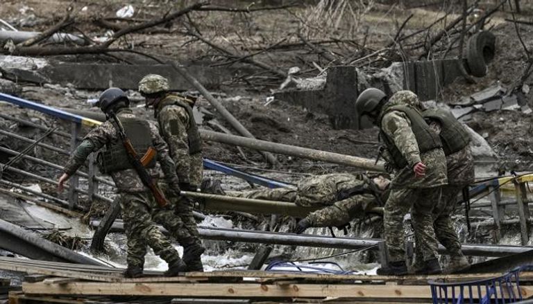 جنود أوكران يحملون أحد الجرحى شمال كييف- أ.ف.ب