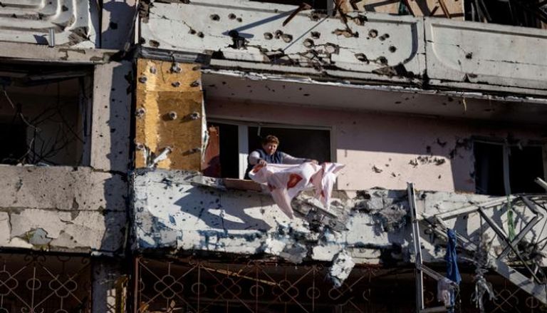 أوكرانية تنظف شرفتها بمبنى سكني دمره القصف (أ. ف. ب)