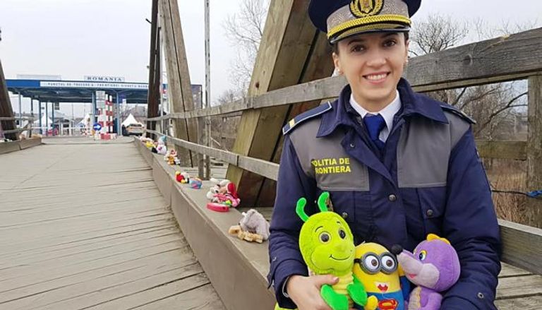 شرطية من حرس الحدود الروماني تحمل الألعاب للأطفال اللاجئين 