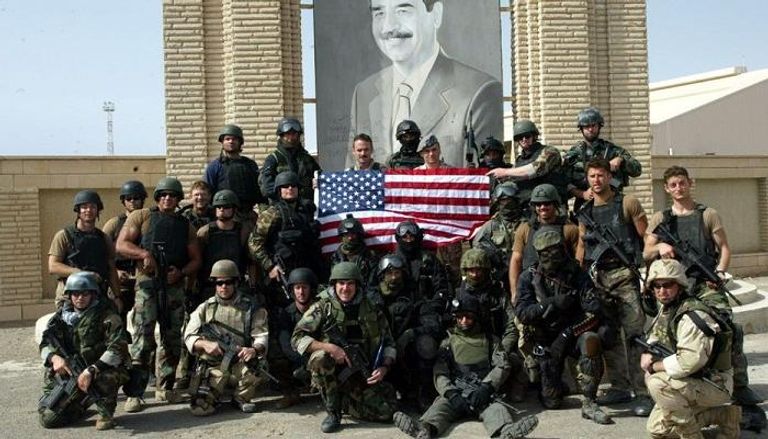 جنود امريكيون وراءهم صورة لصدام حسين في بغداد عام 2003
