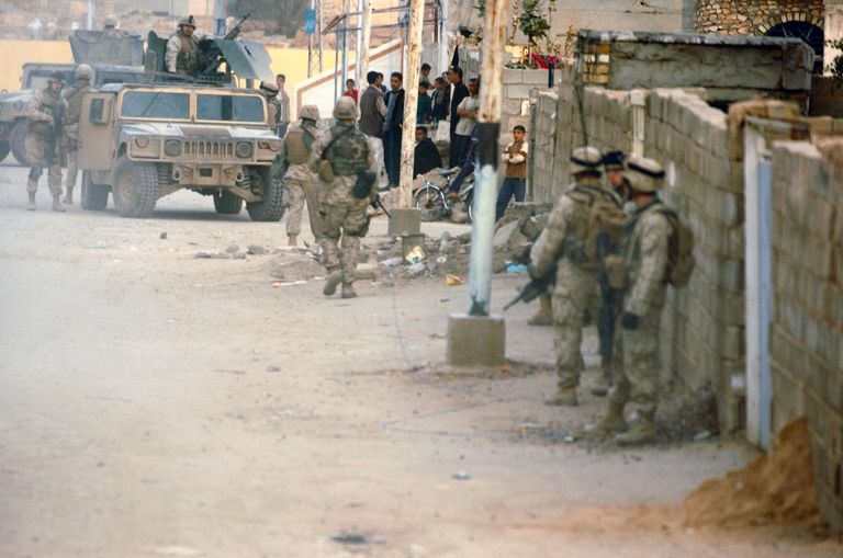 من ذكريات حرب 2003 في العراق جنود أمريكيون ومن ورائهم صورة لصدام حسين في بغداد عام 2003