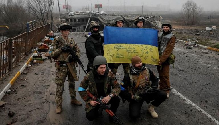 جنود أوكرانيون على جسر مدمر قرب كييف - رويترز