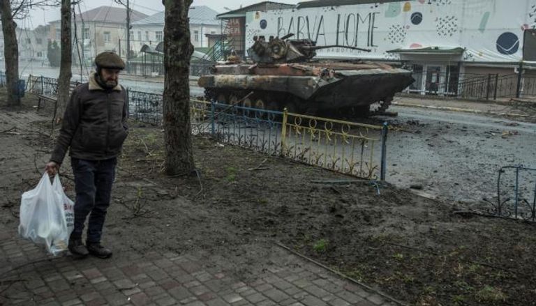 مواطن أوكراني يمر قرب آلية معطوبة مع استمرار العملية الروسية