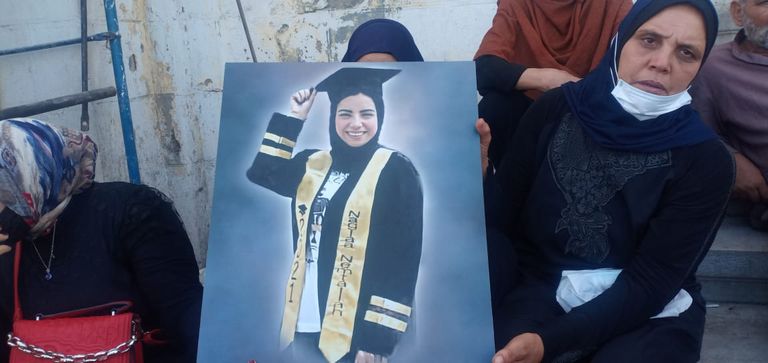 أسرة المجني عليها تحمل صورتها