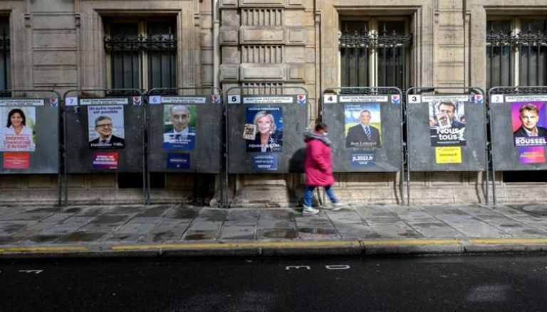 امرأة أمام ملصقات حملة مرشحي الرئاسة الفرنسية - أ. ف. ب