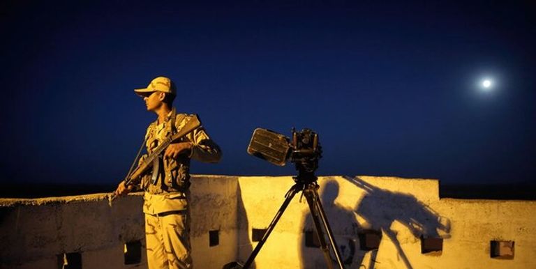 عنصر من حرس الحدود الإيراني عنصر من طالبان أمام معبر حدودي مع إيران