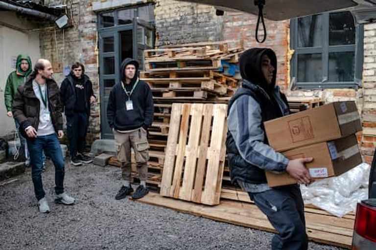 نشطاء يقومون بتفريغ المساعدات متطوعة وسط أجزاء الطائرات المسيرة