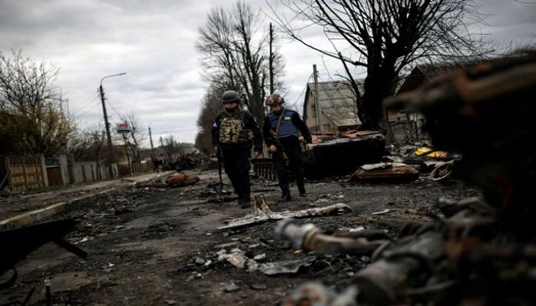 عناصر من الجيش الأوكراني يسيرون بجوار دبابات روسية مدمرة- رويترز