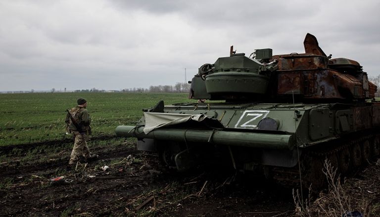 عناصر من الجيش الأوكراني يسيرون بجوار دبابات روسية مدمرة- رويترز