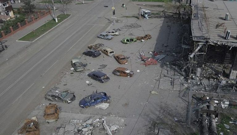 سيارات محطمة بالقرب من مبنى مدمر في ماريوبول الأوكرانية