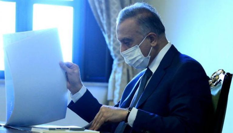 الكاظمي يتصفح الورقة البيضاء وزير المالية العراقي على هامش المشاركة في اجتماعات واشنطن