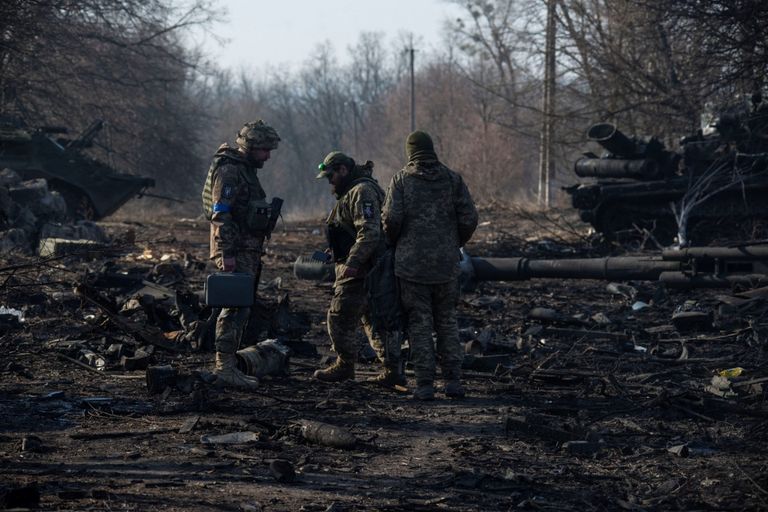 جنود أوكرانيون يتفقدون المركبات العسكرية الروسية المدمرة بالقرب من بلدة تروستيانتس في منطقة سومي سيدة أوكرانية تسير وسط الدمار - رويترز