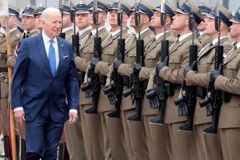 الرئيس الأمريكي جو بايدن يتفقد حرس الشرف خلال حفل ترحيب قبل الاجتماع مع الرئيس البولندي أندريه دودا سيدة أوكرانية تسير وسط الدمار - رويترز