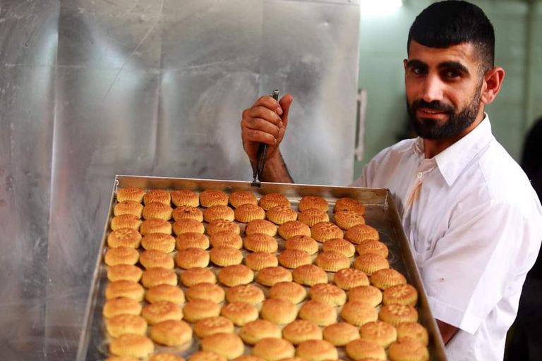 شاب فلسطيني يحمل طاولة الكعك المزركش مخبز يعرض الكعك للبيع قبل حلول عيد الفطر