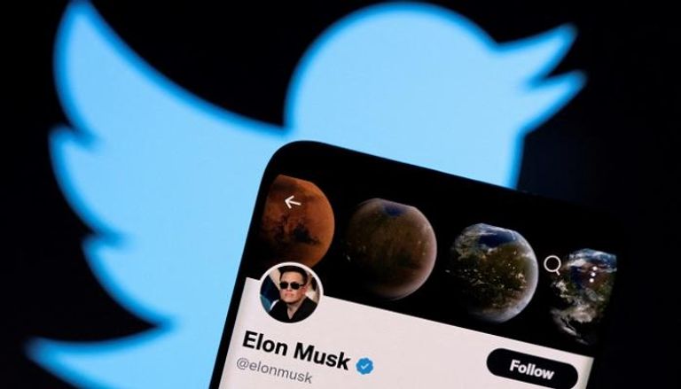 حساب Elon Musk على Twitter على هاتف ذكي أمام شعار تويتر - رويترز
