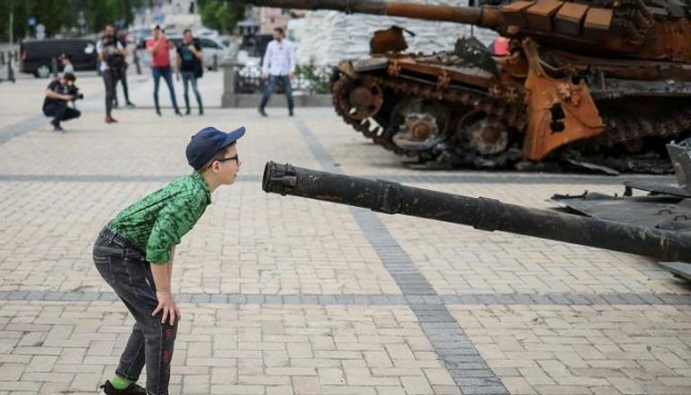 طفل أوكراني يعاين فوهة دبابة روسية- رويترز