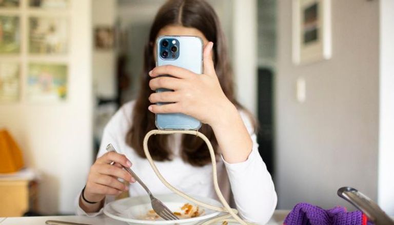 مراهقة تتصفح الإنترنت أثناء تناولها الطعام - أرشيفية