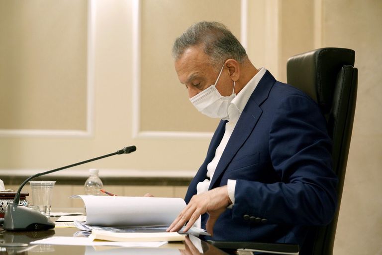 الصورة الأصلية لرئيس وزراء العراق صورة متلاعب فيها لرئيس وزراء العراق يعمل في الظلام