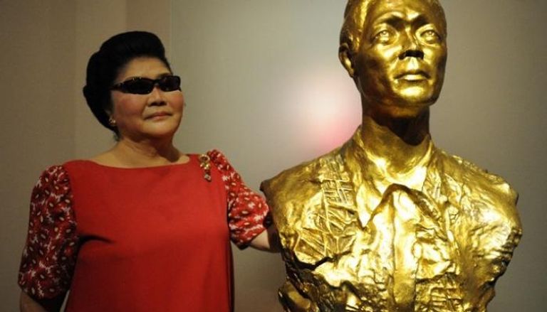 إميلدا ماركوس إلى جانب تمثال لزوجها فرديناند ماركوس