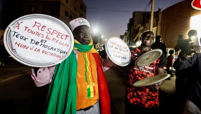 أحد السنغاليين يحمل مجموعة من القوادر خلال احتجاجات المعارضة- رويترز