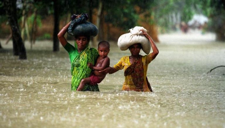 سيدتان تحملان طفلا وسط فيضانات بنجلاديش 