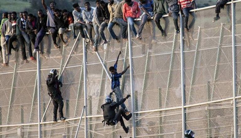 مهاجر يحاول تسلق السياج الحدودي لمدينة مليلية - أرشيفية