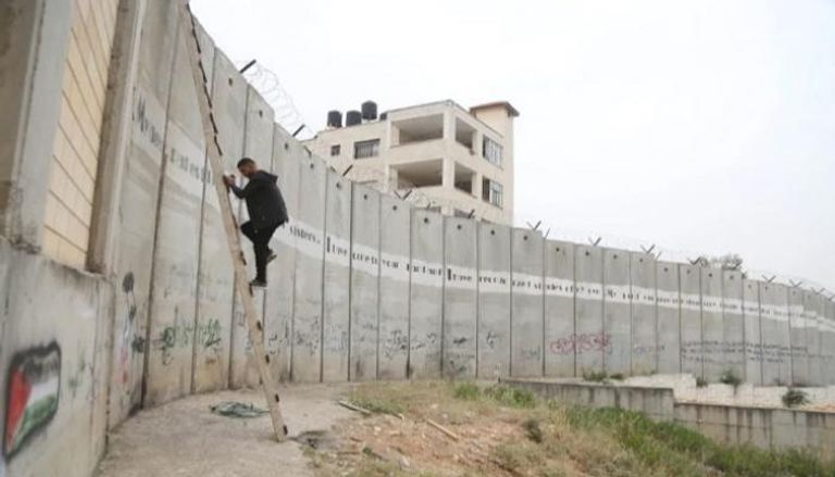 أحد الفلسطينيين يحاول عبور الجدار الفاصل- أرشيفية