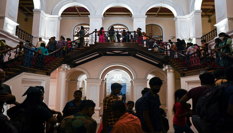 رجل يلوح بعلم سريلانكا خارج إقامة الرئيس في كولومبو (أ ف ب)