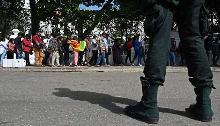 رجل يلوح بعلم سريلانكا خارج إقامة الرئيس في كولومبو (أ ف ب)