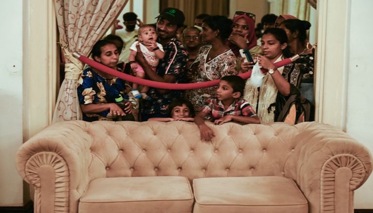 رجل يلوح بعلم سريلانكا خارج إقامة الرئيس في كولومبو (أ ف ب)