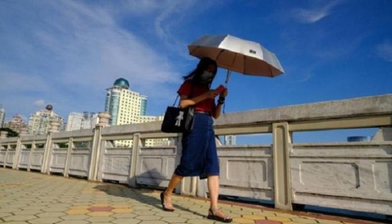 سيدة تسير في أحد شوارع شنغهاي - وكالات