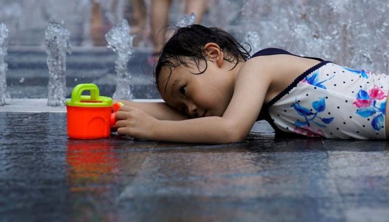 طفلة صينية قرب نافورة مياه لمواجهة الحر ظواهر التغير المناخي تهدد سلة غذاء العالم