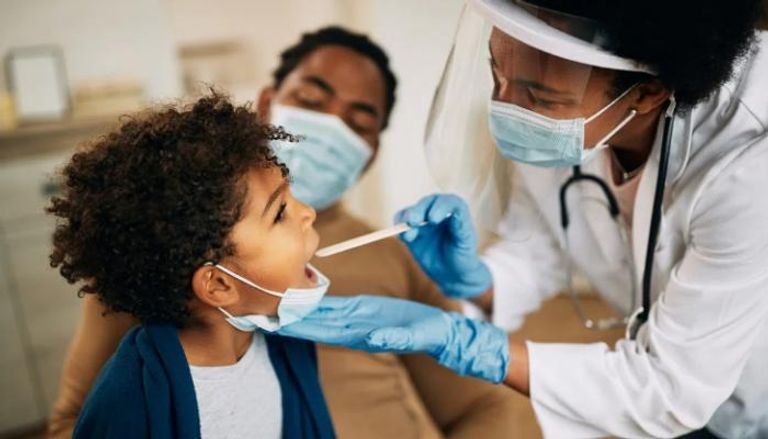 طبيبة تفحص طفلا يتشبه في إصابته بفيروس كورونا - تعبيرية