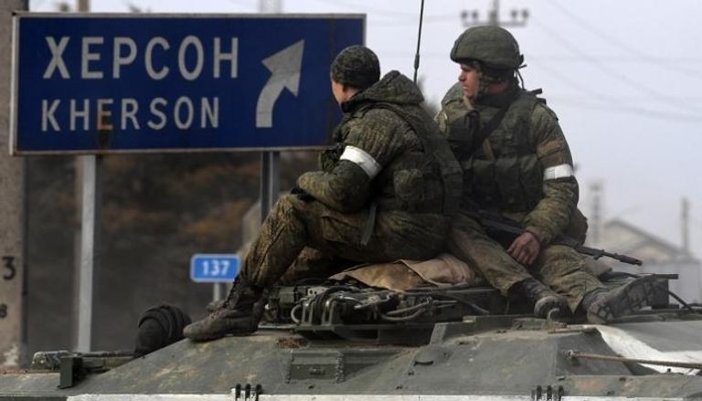 قوات روسية أمام لافتة تؤدي لمدينة خيرسون الأوكرانية