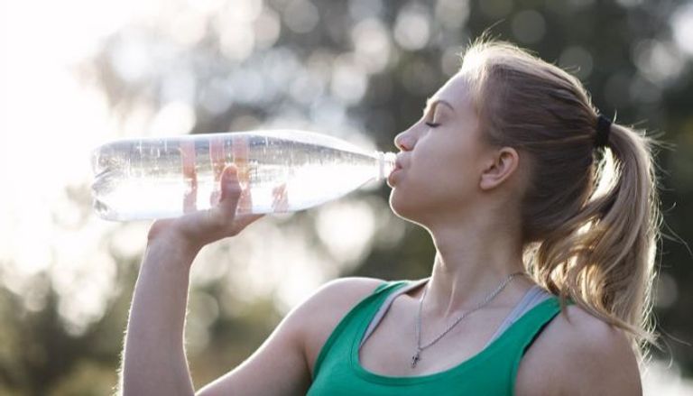 شابة تشرب الماء بعد تمرين رياضي