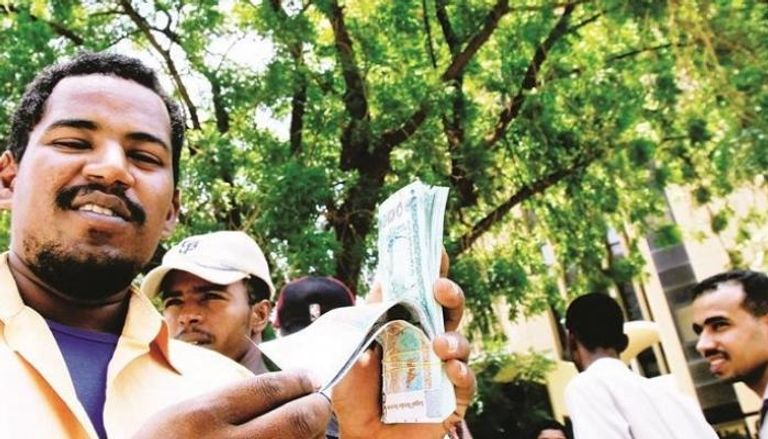 سودانيون يحملون فئات نقدية من الجنيه السوداني